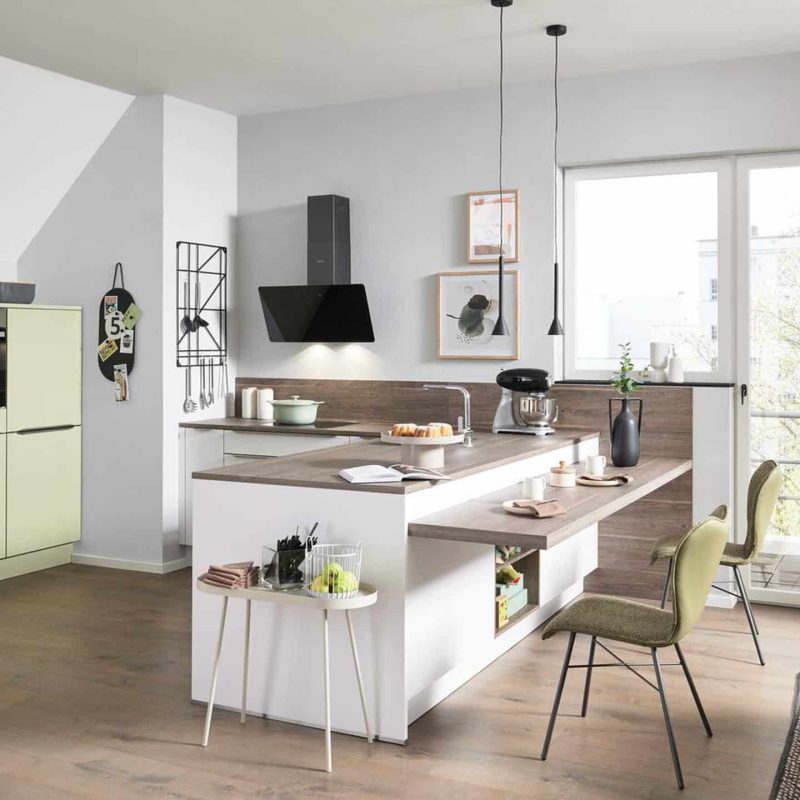 Moderne Interliving Küche mit hellgrünen Schränken und Kochinsel. Minimalistisches Dekor und große Fenster.